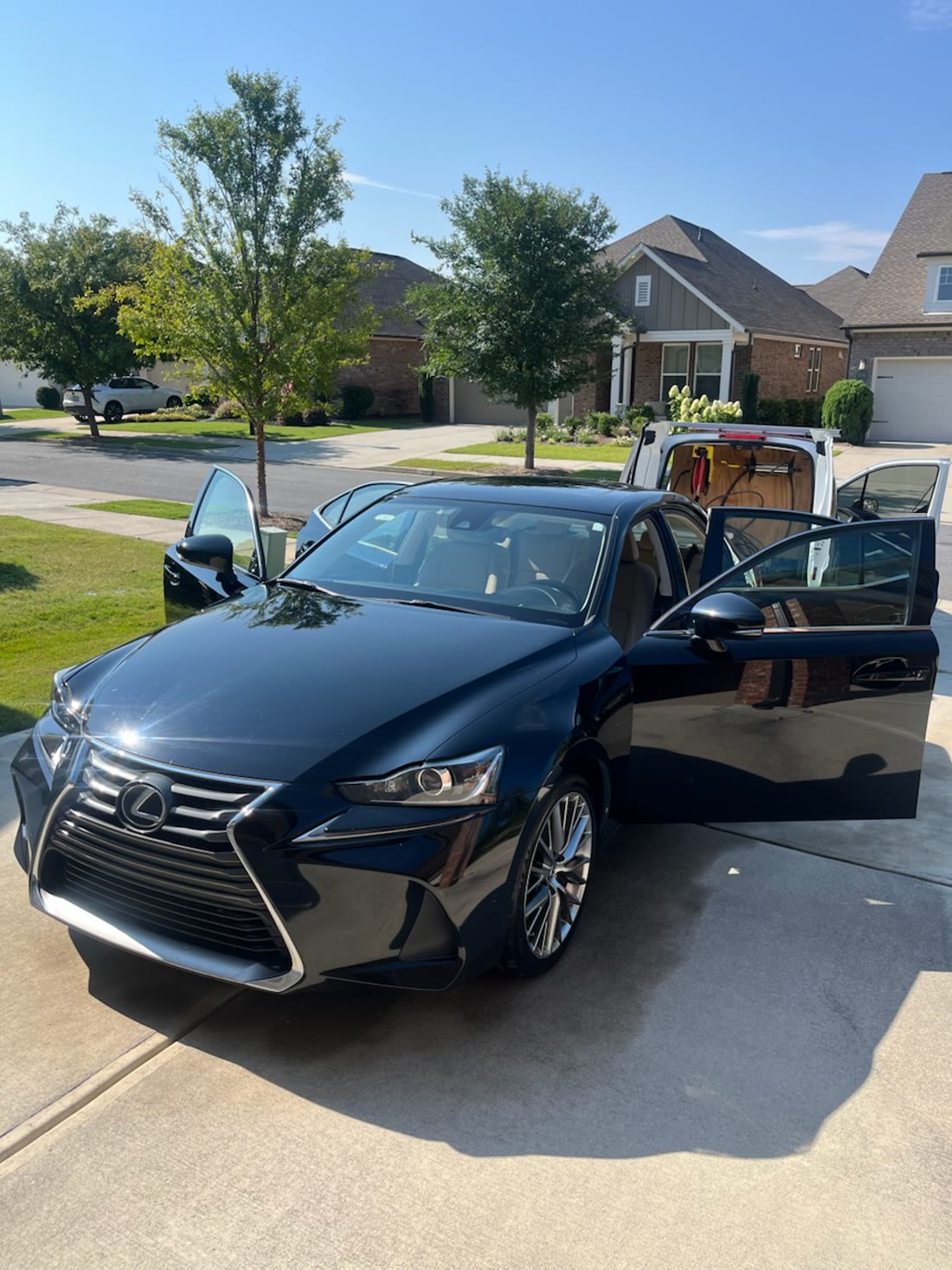 A black Lexus IS with its doors open, the Peachtree Mobile Detail van parked behind it in an Atlanta driveway